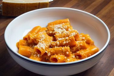 A white bowl of penne alla vodka sprinkled with cheese