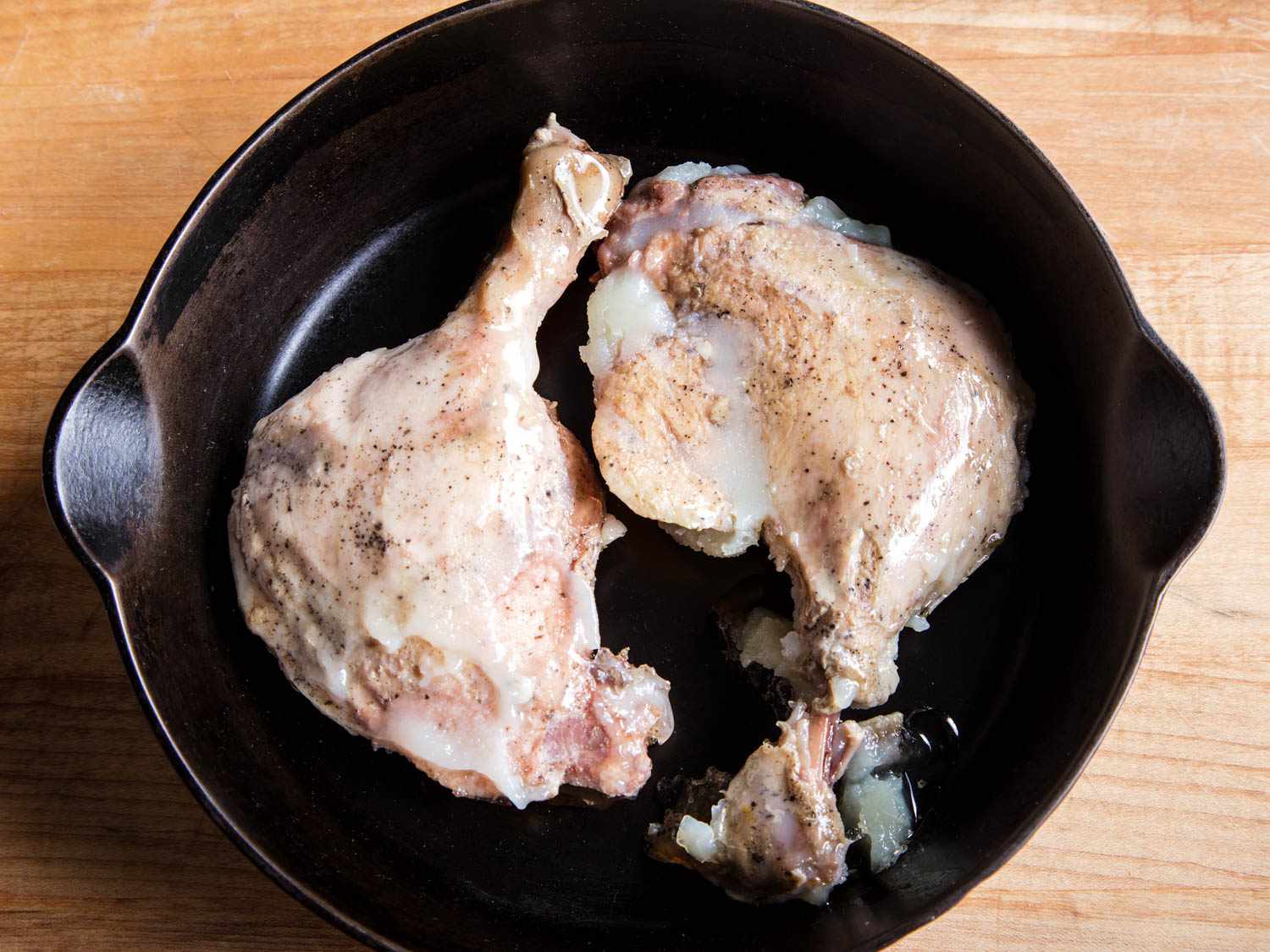 Overhead shot of confit duck legs in a cast iron pan.
