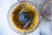 Finely chopped pistachios in the bowl of a mini food processor.