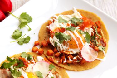 Sweet potato tacos topped with fried egg and drizzled with crema