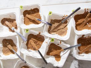 Assorted samples of almond butter in containers with small spreading knives