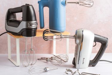 Three hand mixers on a white kitchen countertop.