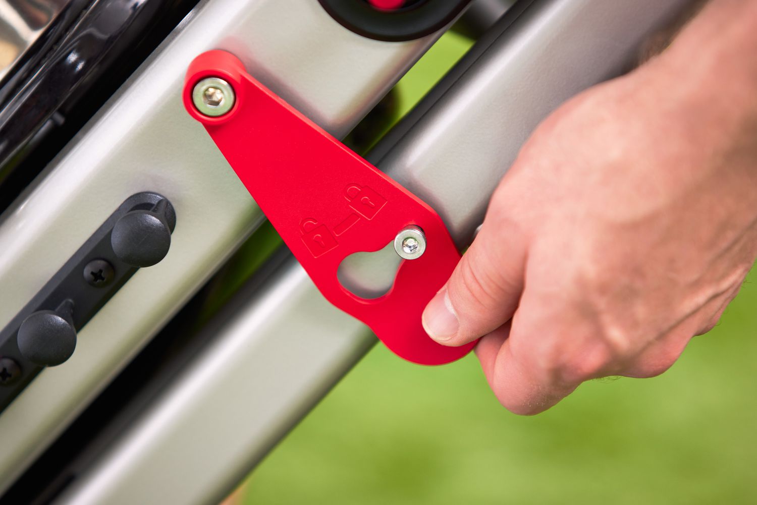 A closeup of a hand locking the Weber Traveler Portable Gas Grill.