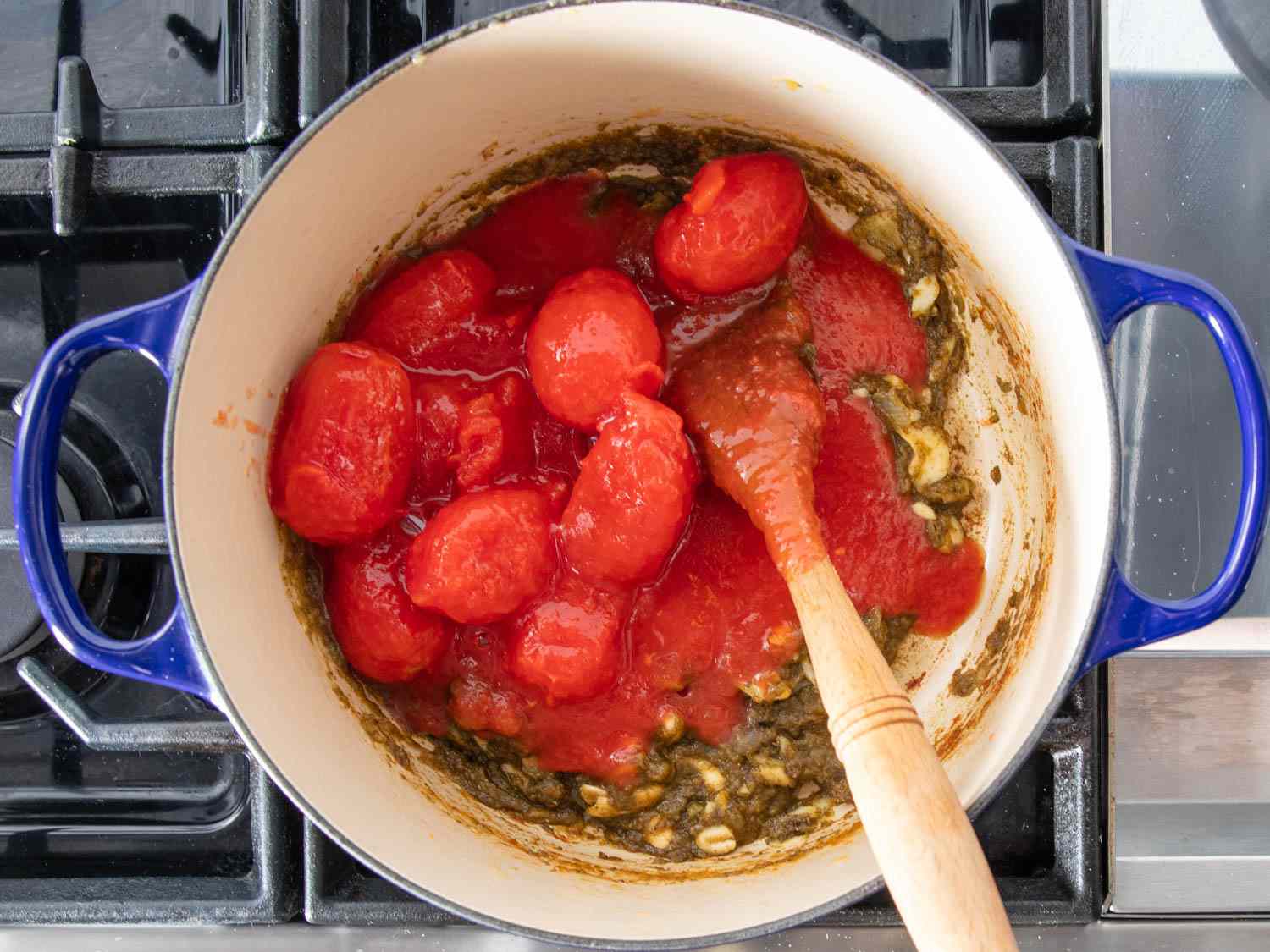 Overhead view of the aromatics and tomatoes cooking in a Dutch oven.