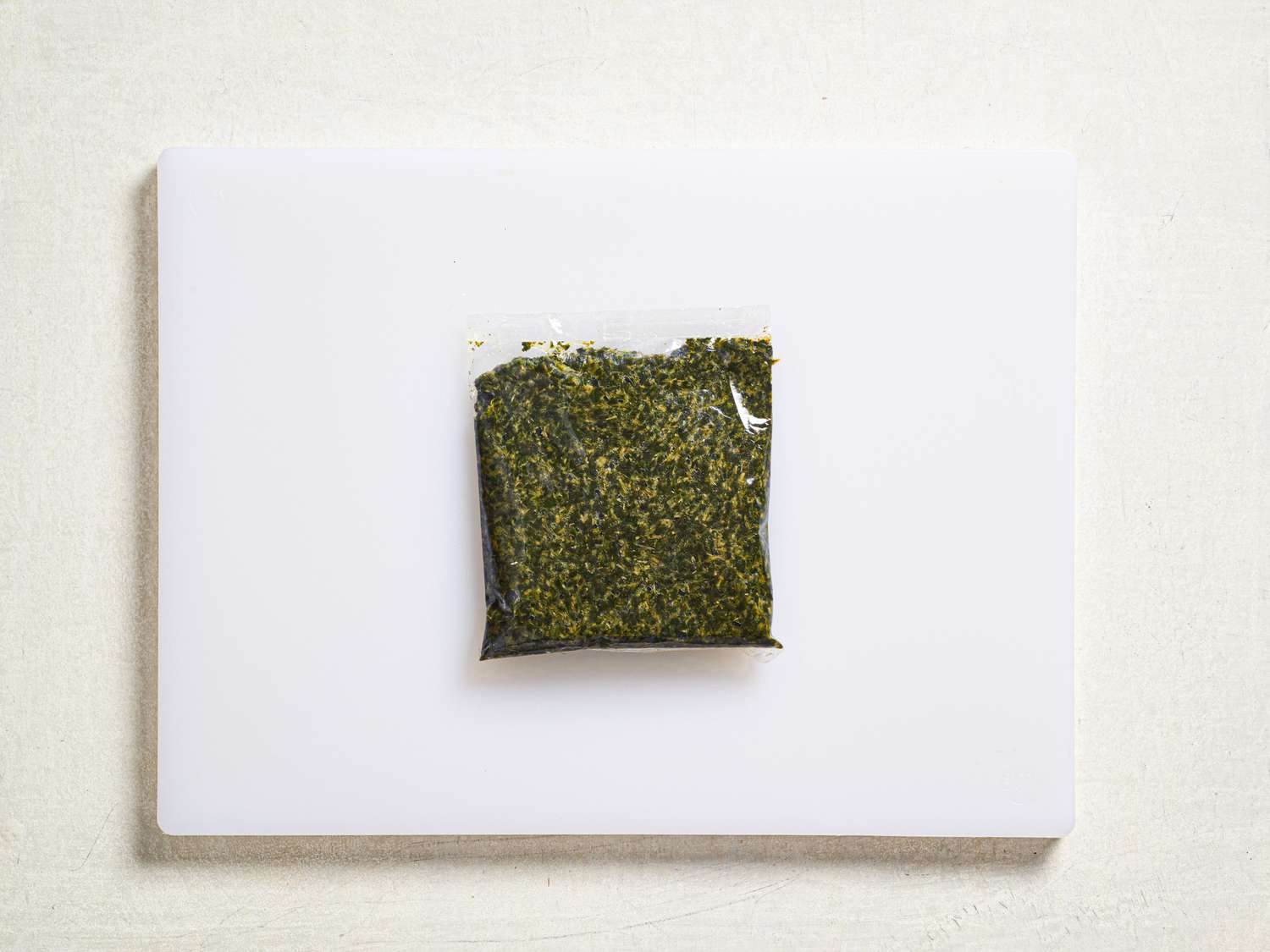 Molokhia leaves in a plastic bag on a cutting board.