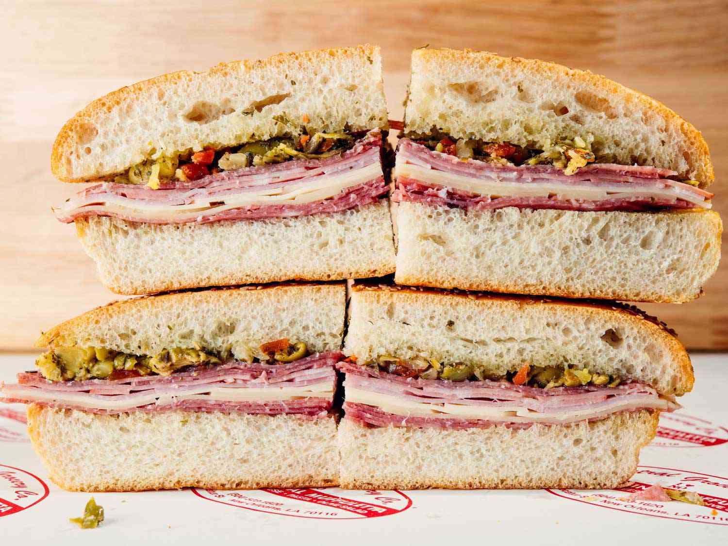 The muffuletta sandwich at Central Grocery, split into quarters and stacked so the layers of meat, cheese, and olive salad are visible.