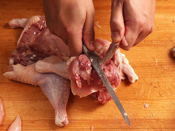 Using the knife's hilt to scrape away meat from thigh bone