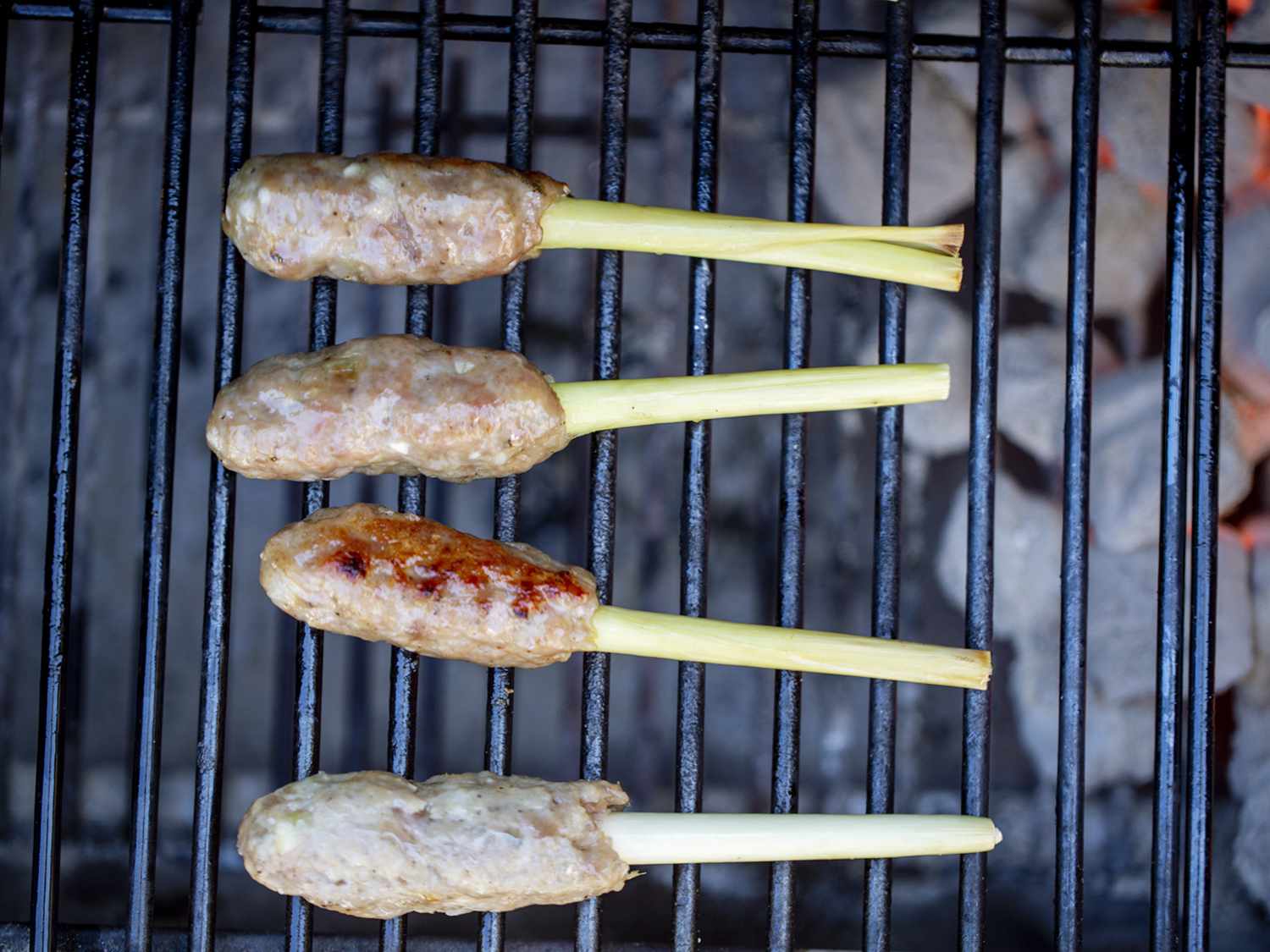 Nem lui skewers on a grill after being cooked through via indirect heat