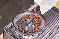 Espresso beans are poured into the Breville The Oracle Dual Boiler Espresso Machine grinder