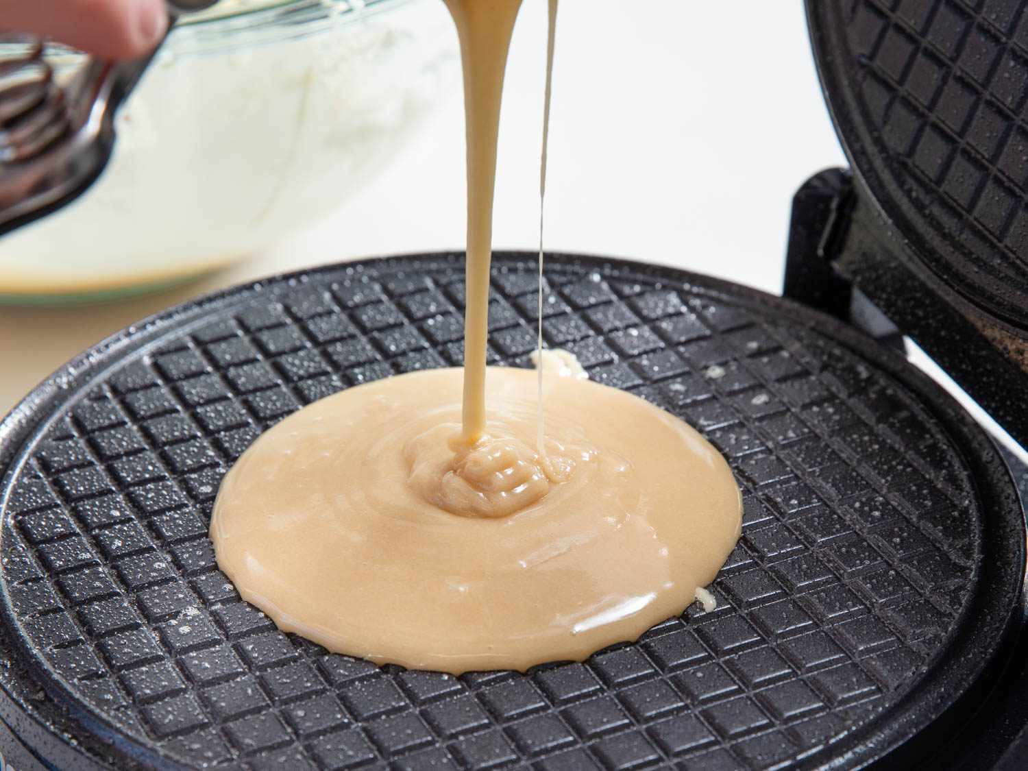 Portioning batter onto a waffle cone iron.