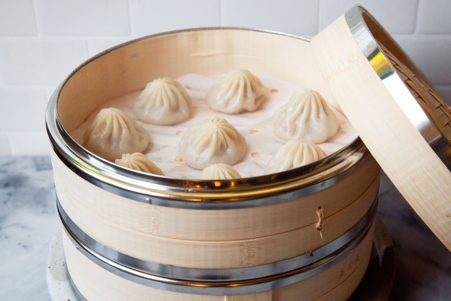 bamboo steamer basket with lid off showcasing soup dumplings inside