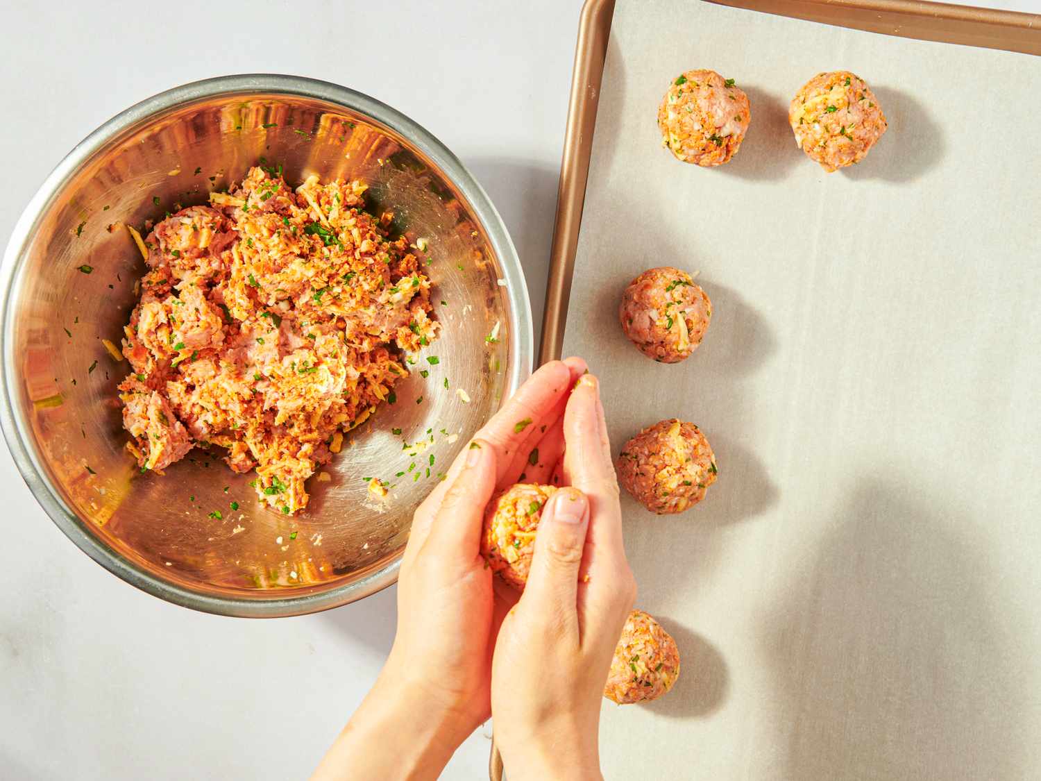 Shaping turkey mixture into meatballs next to a tray