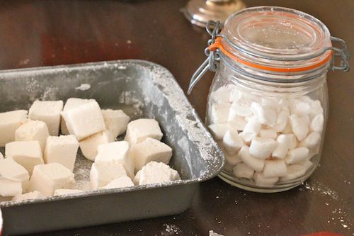 A baking pan full of homemade marshmallows, as well as a jar of mini marshmallows.