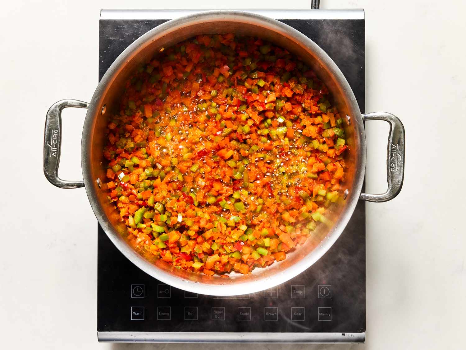 A pot of diced vegetables cooking on an induction stove