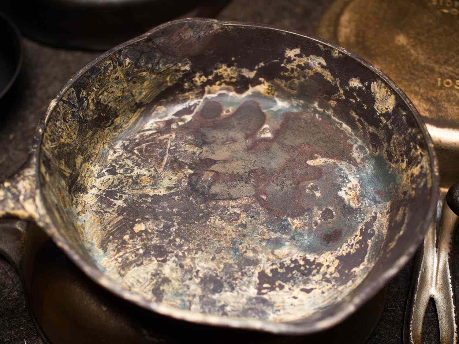 A cast iron skillet covered in dried Naval jelly.