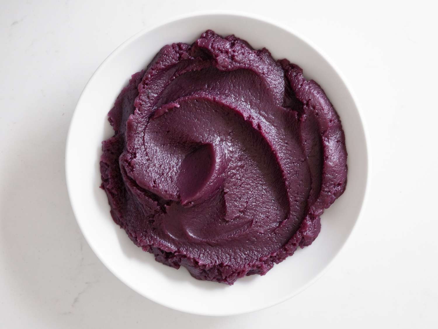 Overhead view of the finished ube halaya, transferred to a shallow white bowl.