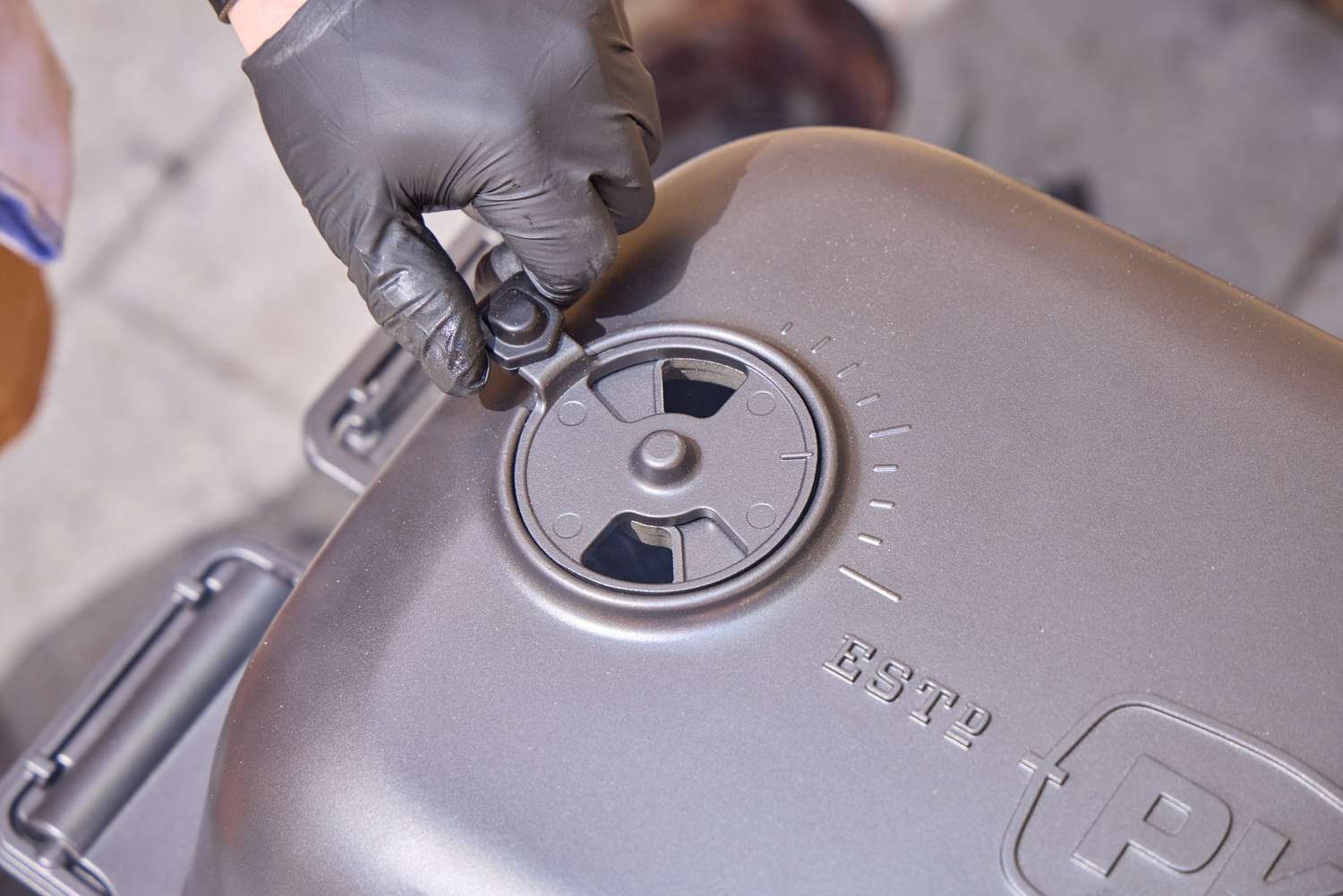 A hand touching the top of the PK Grills Original PK300 Grill & Smoker 