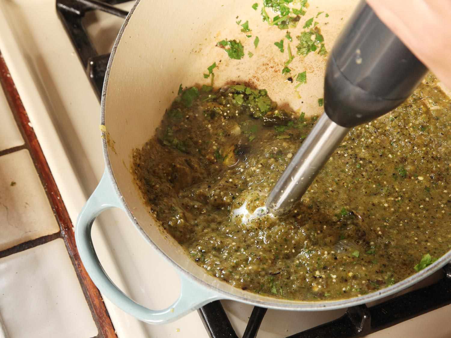 The broiled and peeled green chiles, tomatillos, etc. are transferred to the Dutch oven and puréed with an immersion blender.