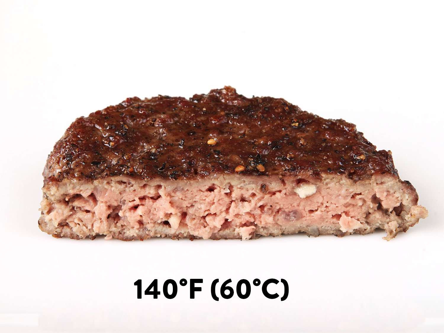A sous vide hamburger cooked to 140F (medium-well) and cut in half to show light pink and relatively dry interior.