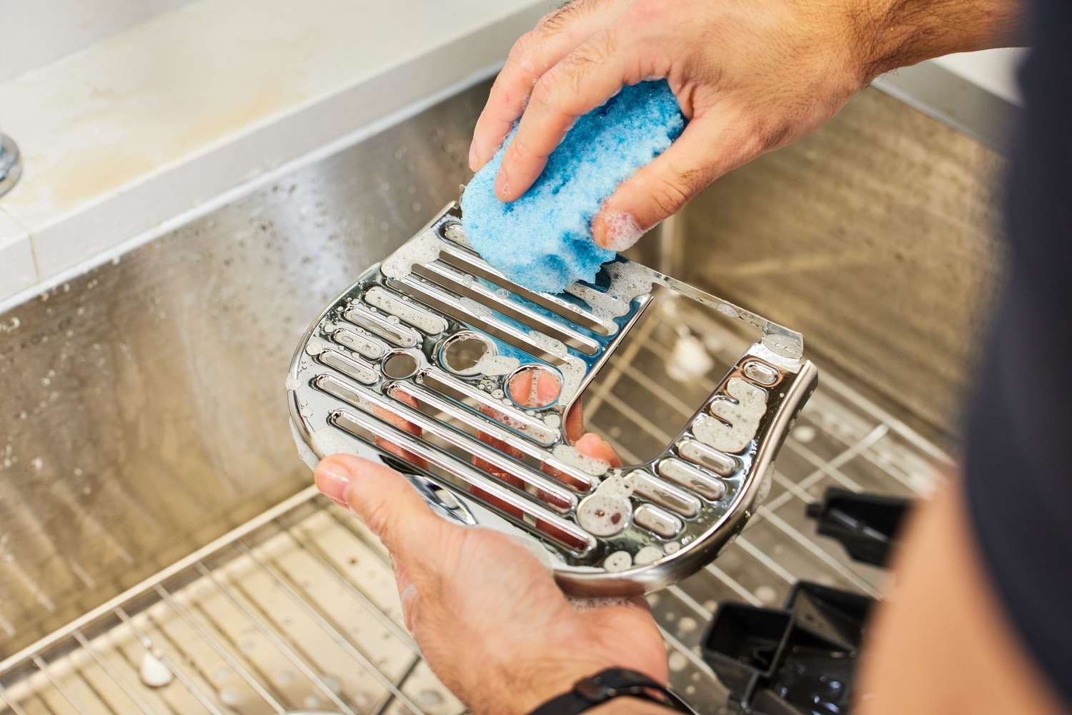Hand cleaning Breville Bambino Plus Espresso Machine tray with blue sponge
