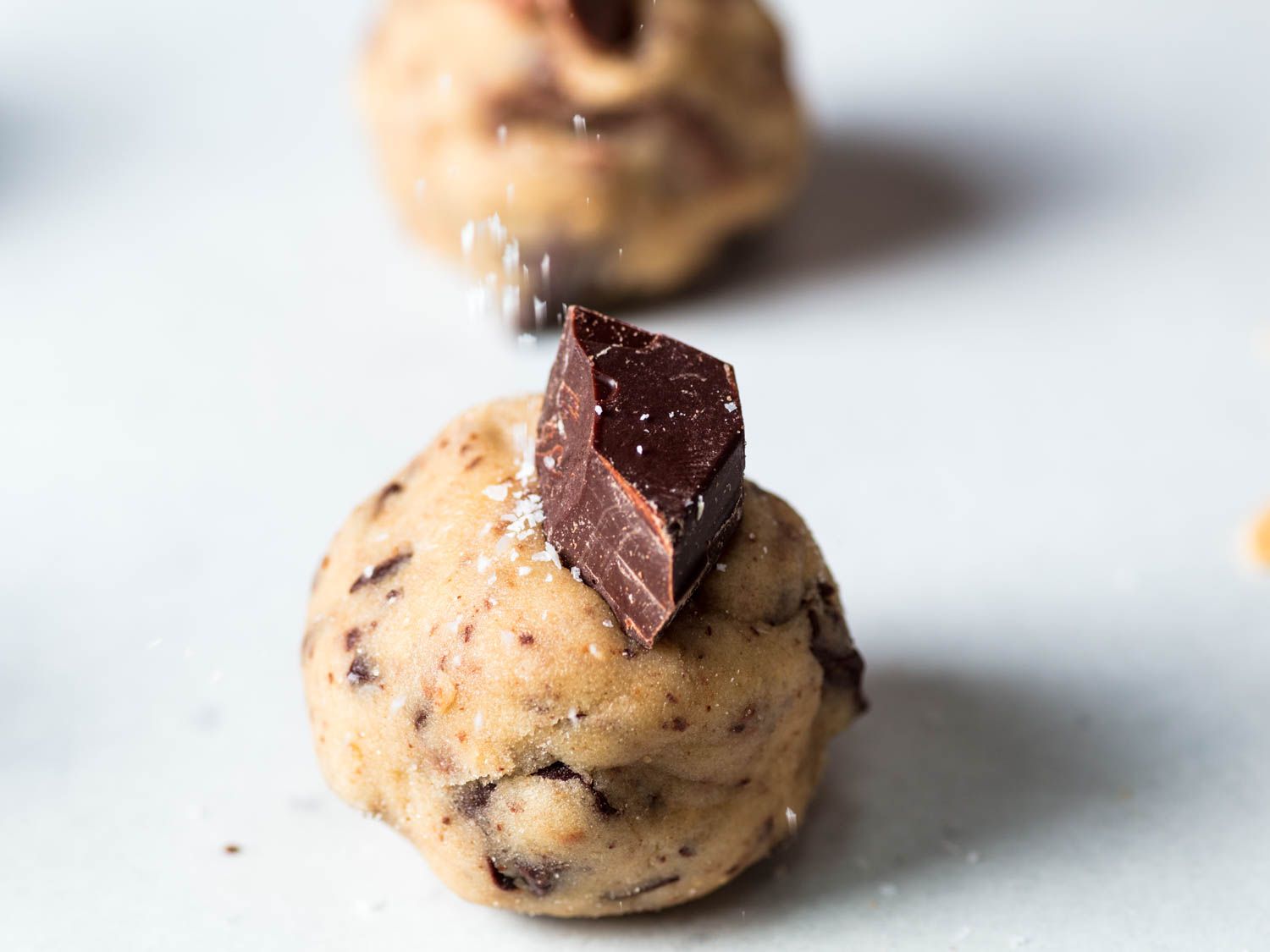 Sprinkling salt on a portion of chocolate chip cookie dough.