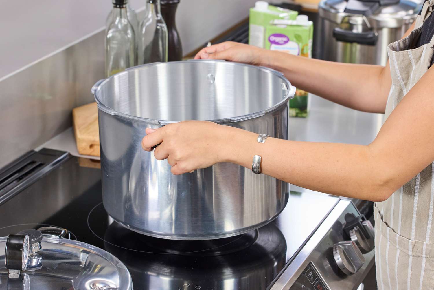 A person places the Presto 16-Quart Pressure Canner and Cooker onto a stovetop