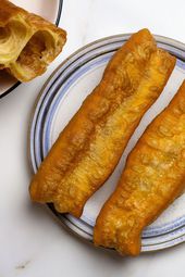 Youtiao on a plate next to a platter of youtiao