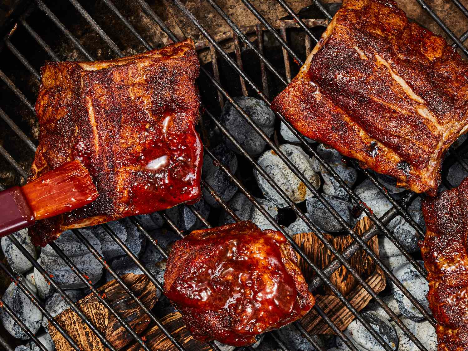 Barbecue ribs and meat on a grill with sauce being applied