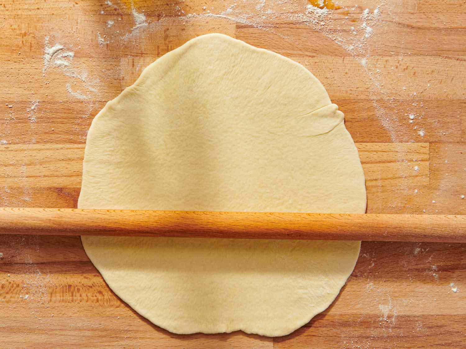 Rolling pin and rolledout dough on a wooden surface