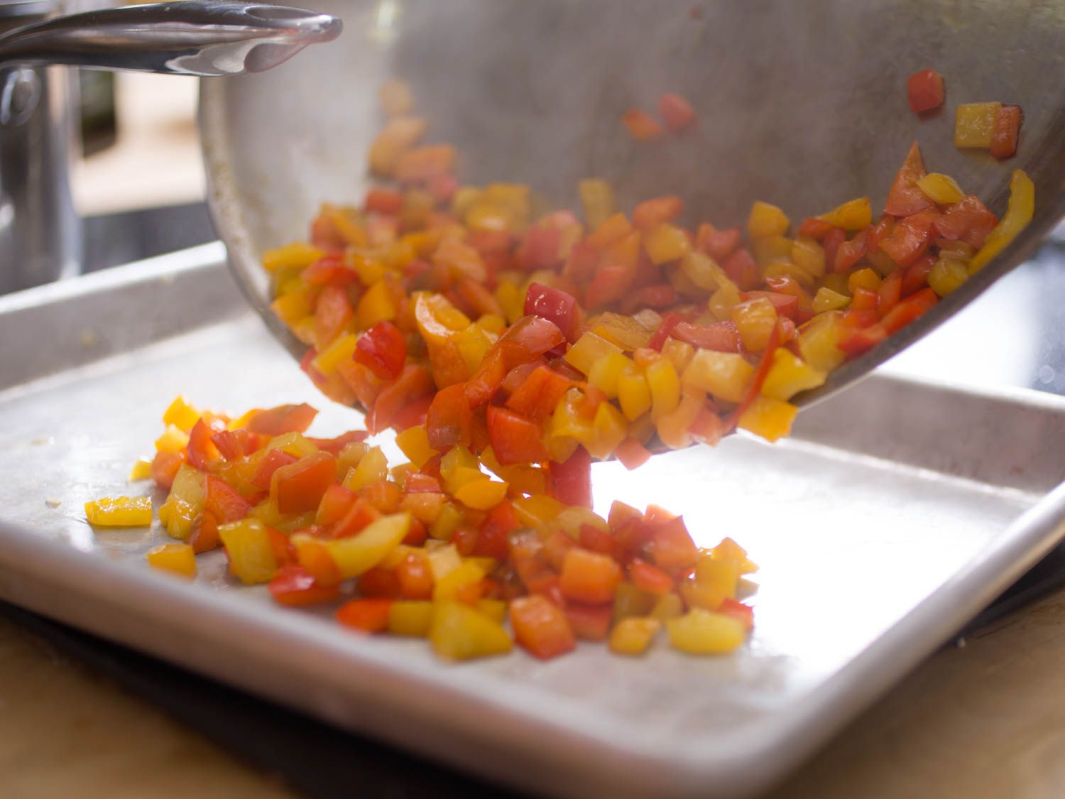 Author transferring cooked bell pepper to a rimmed baking sheet to cool.