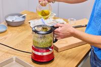 a person pours oil into a food processor