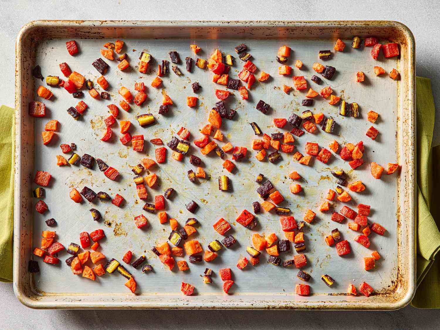 Diced roasted vegetables spread on a baking sheet