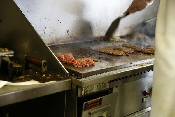 Patties being griddled and smashed at a Five Guys location.