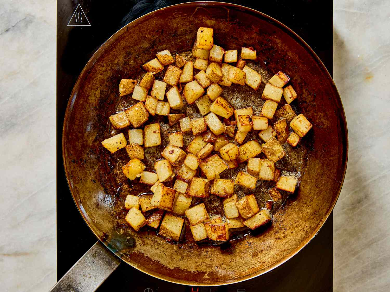 Diced potatoes cooking in a pan on a stovetop