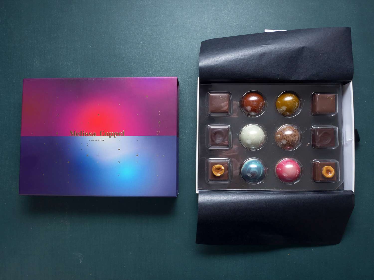 Melissa Coppel chocolates unboxed with the pink and blue sleeve next to the chocolate container