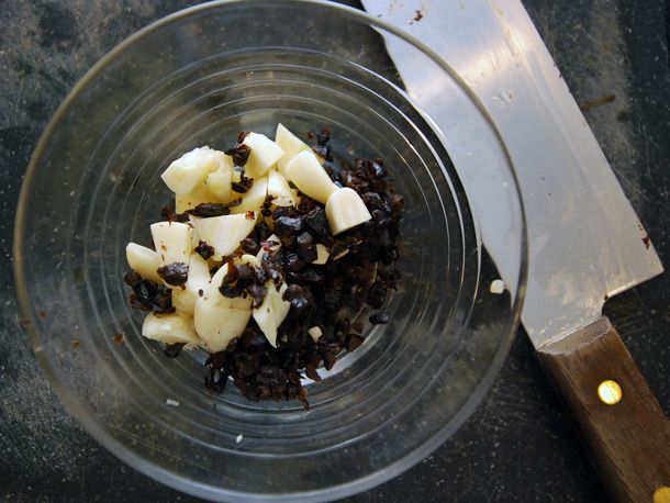 Coarsely chopped garlic in a glass bowl with some fermented black beans.