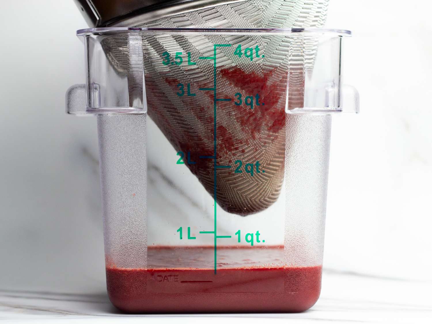 Profile view of the blended sauce being strained into a Cambro container.