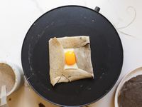 a folded buckwheat crepe with an egg on the electric crepe pan
