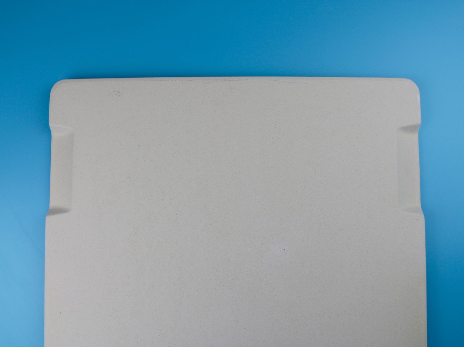 a pizza stone with two handle indents on the side