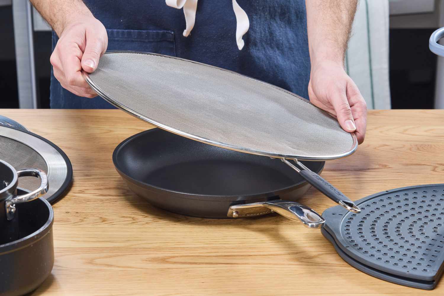 a person placing the bergkoch splatter screen over a skillet
