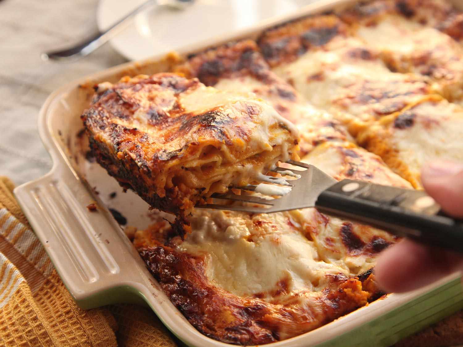 Lifting a portion of squash lasagna out of the baking dish.