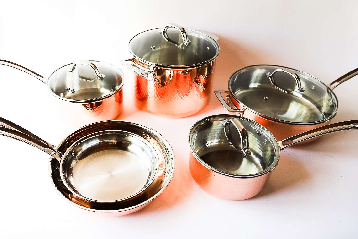 A set of copper cookware including pots and pans with lids