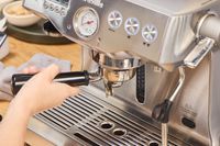 A person makes espresso using the Breville BES920XL Dual Boiler Espresso Machine