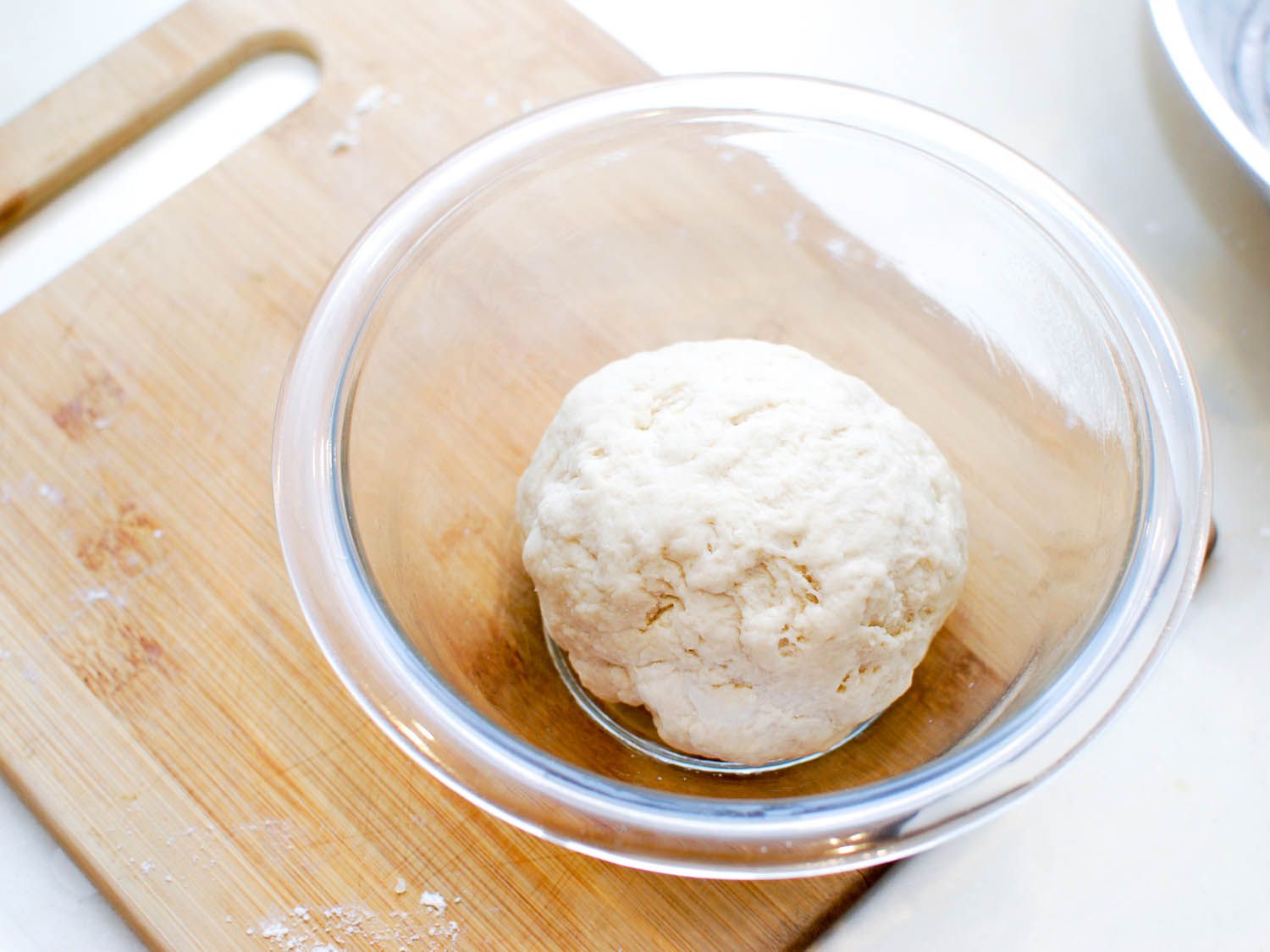 The mixed sheng jian bao dough, kneaded into a ball and left to rest in a small glass bowl.