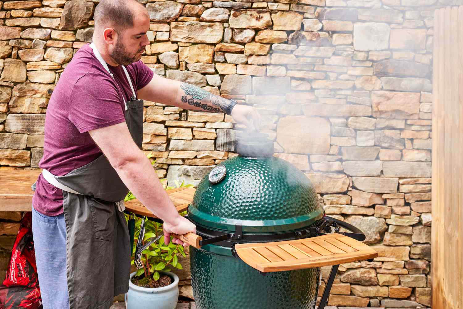 A person opens a valve on the Big Green Egg Large Charcoal Kamado Grill and Smoker