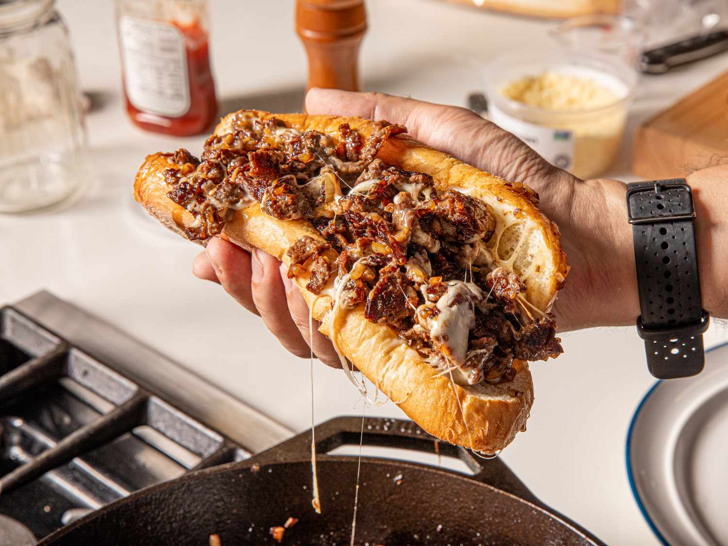 A hand holding a freshly made cheesesteak 