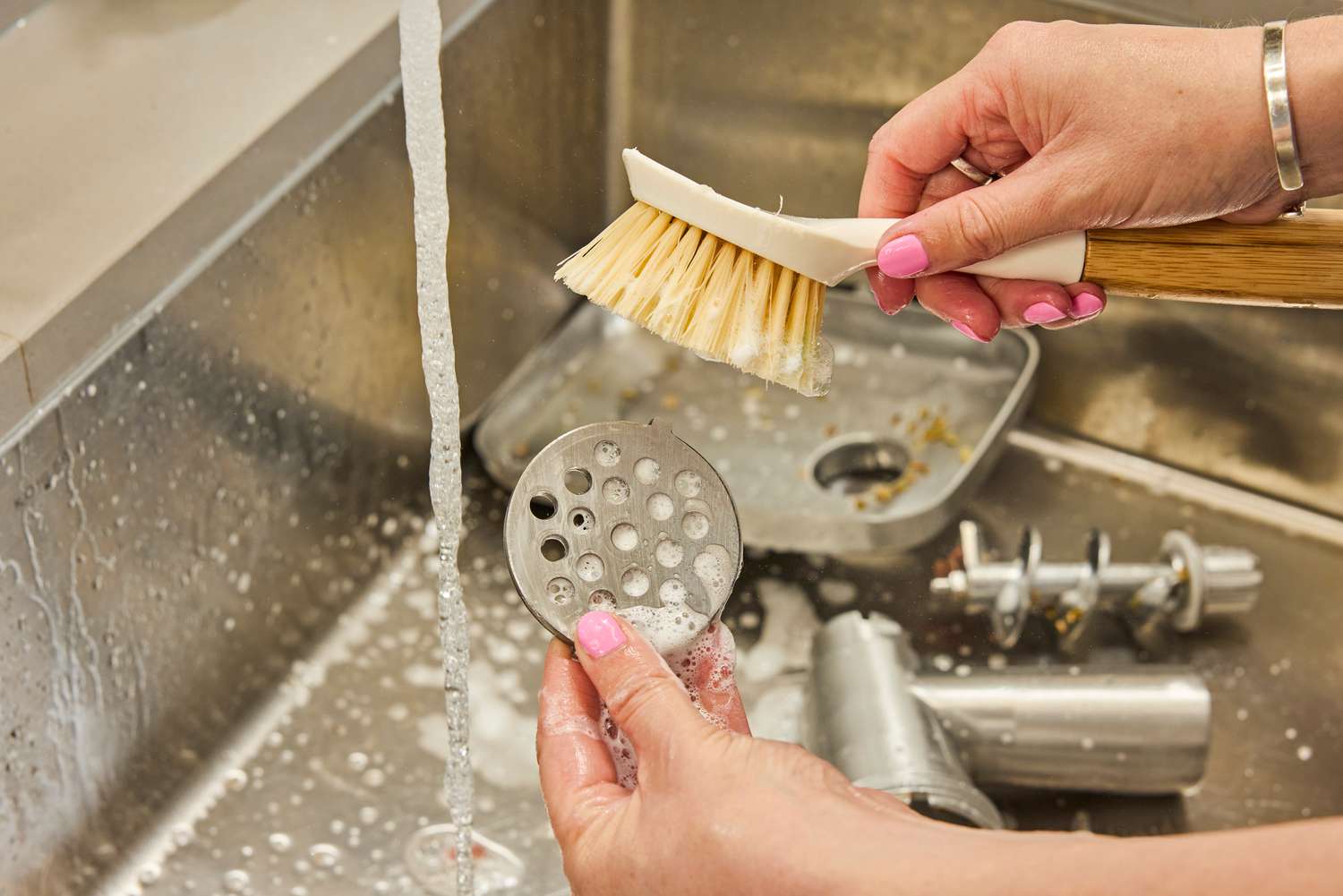 Person cleaning grinding plate of Weston #12 Electric Meat Grinder & Sausage Stuffer