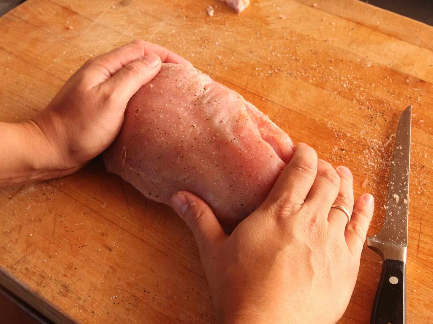 Pressing two seasoned, raw turkey breast lobes together before cooking sous vide.