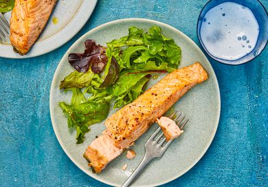 Overhead view of air-fryer salmon, served on an earthenware plate with a simple green salad.