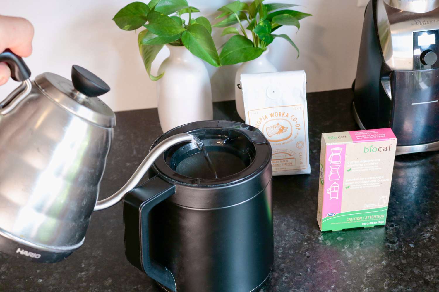 A gooseneck kettle pouring hot water into a thermal carafe
